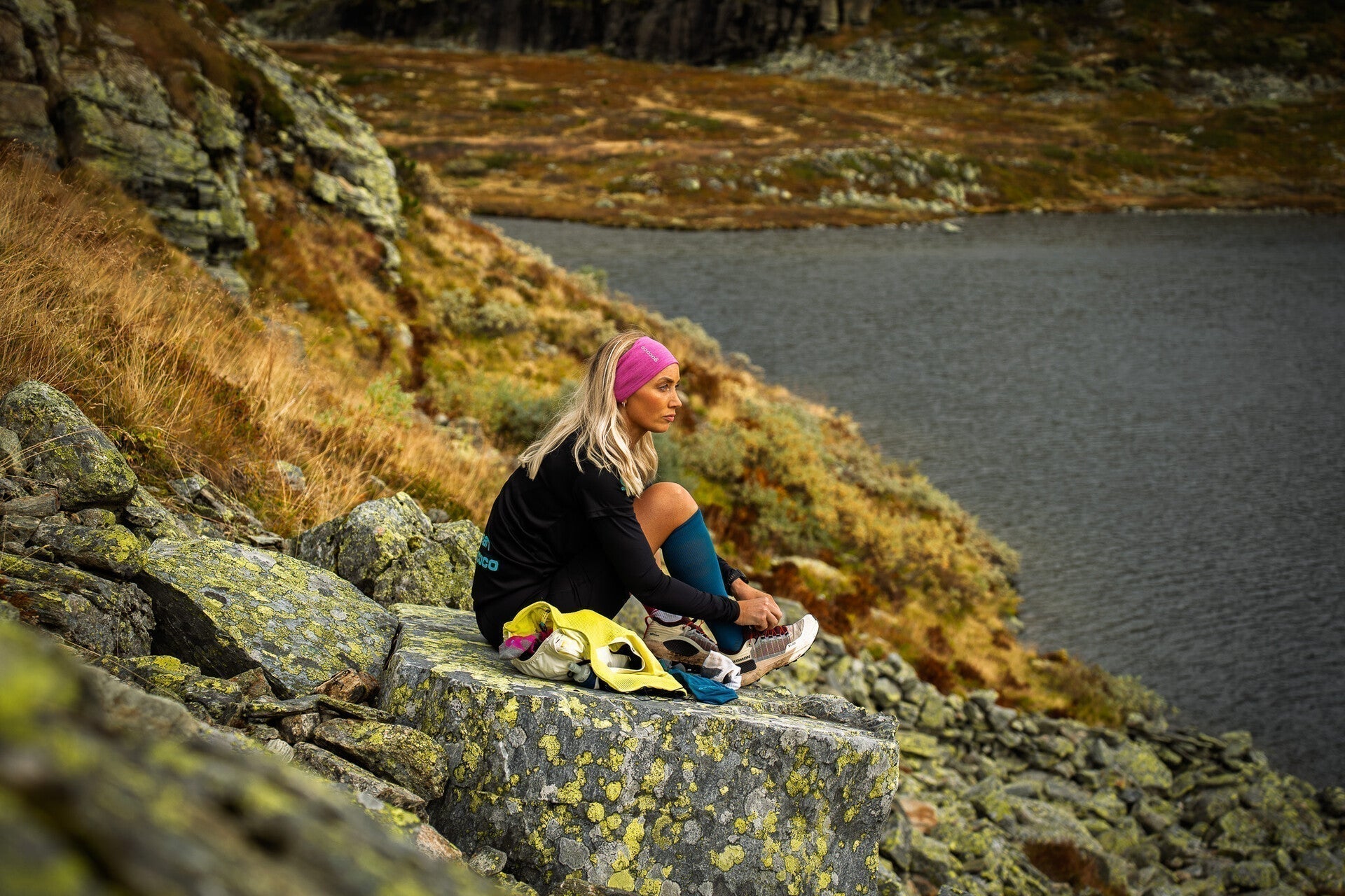 Tjej sitter på en klippa på fjället och har kompressionsstrumpor på benen