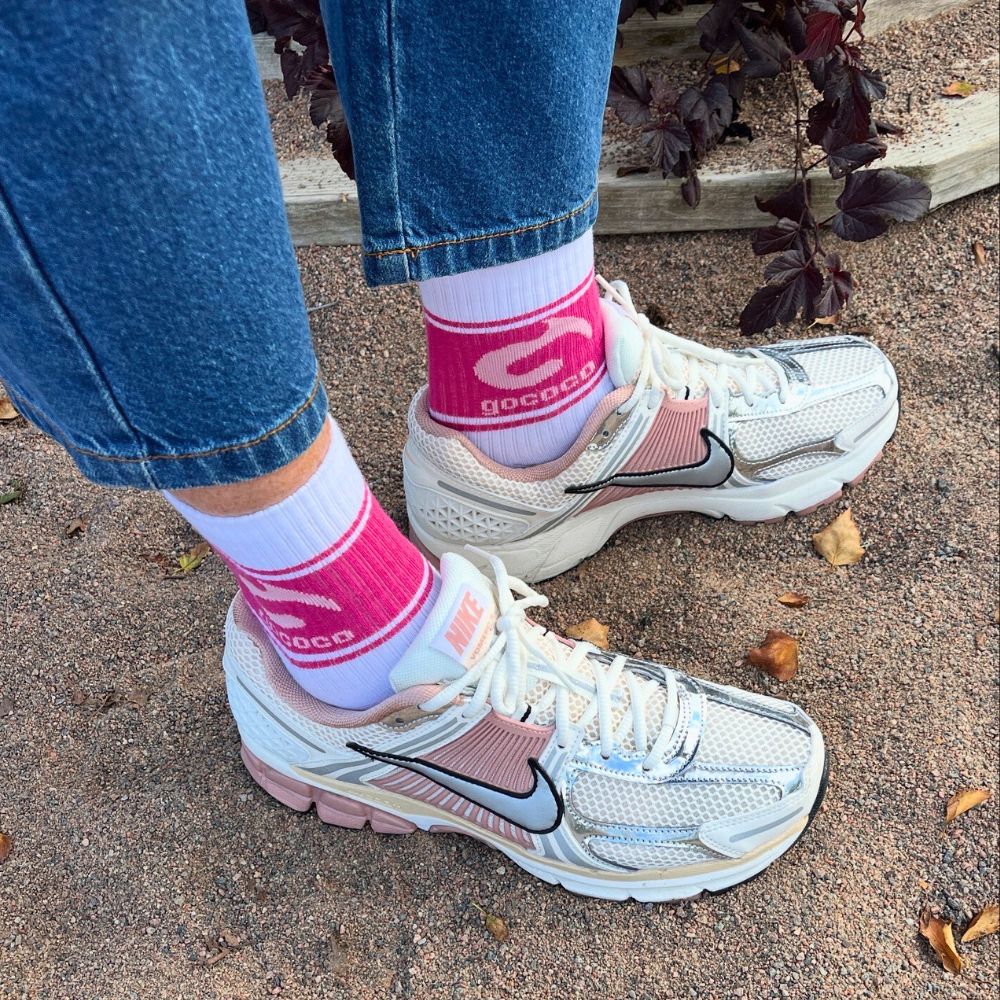 Fötter på sand med gococo sportstrumpor med rosa logga 
