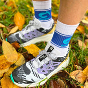 Fötter med Gococo strumpor med blå logga bland höstlöv